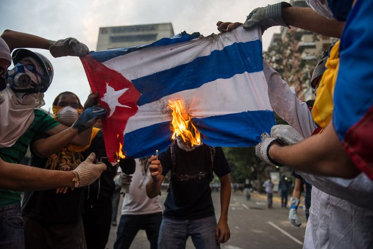 Manifestantes venezolanos queman bandera cubana en protesta contra el intervencionismo cubano. Las protestas fueron fuertemente reprimidas por el régimen madurista. Caracas, marzo 2014. (Foto: CNN) Manifestantes venezolanos queman bandera cubana en protesta contra el intervencionismo cubano. Las protestas fueron fuertemente reprimidas por el régimen madurista. Caracas, marzo 2014. (Foto: CNN)